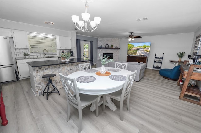 dining space featuring a fireplace, plenty of natural light, visible vents, and ceiling fan with notable chandelier