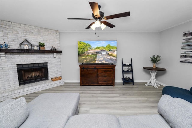 living room with baseboards, a ceiling fan, wood finished floors, a fireplace, and ornamental molding