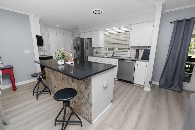 kitchen featuring ornamental molding, appliances with stainless steel finishes, a breakfast bar area, and a sink