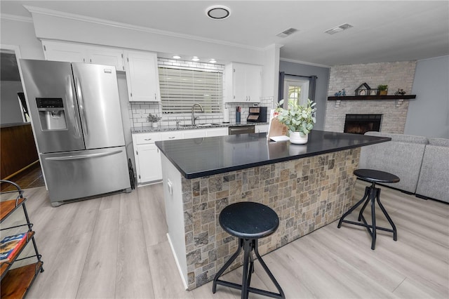 kitchen with visible vents, a sink, light wood-type flooring, a kitchen bar, and appliances with stainless steel finishes