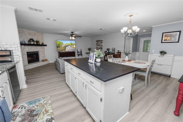 kitchen featuring white cabinets, visible vents, ceiling fan with notable chandelier, a large fireplace, and dishwasher