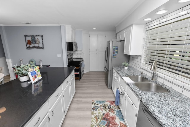 kitchen with crown molding, a sink, stainless steel appliances, white cabinets, and backsplash