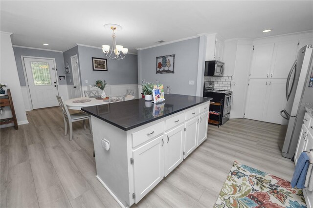 kitchen with white cabinets, ornamental molding, light wood-style floors, appliances with stainless steel finishes, and a notable chandelier