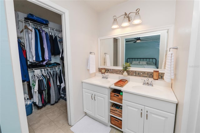 bathroom with a walk in closet, a ceiling fan, a sink, and double vanity