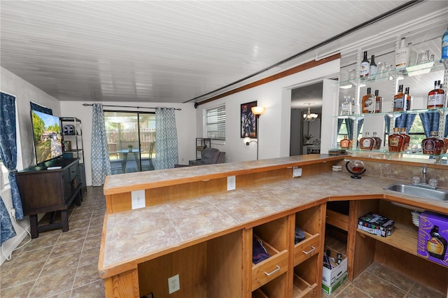 kitchen with tile counters, an inviting chandelier, and a sink