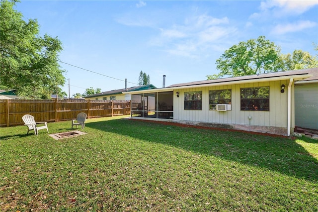 back of house with a fenced backyard, a fire pit, a sunroom, and a yard