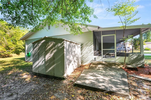 view of property exterior featuring an outdoor structure, a storage unit, and a sunroom