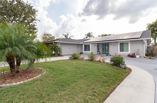 ranch-style house with solar panels, a garage, a front lawn, and curved driveway