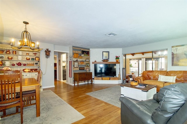 living area with baseboards, light wood-style flooring, visible vents, and a chandelier