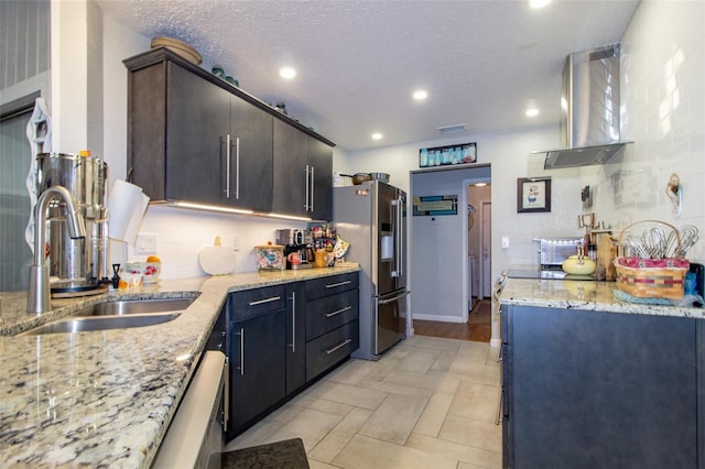 kitchen featuring high end fridge, backsplash, a sink, visible vents, and wall chimney range hood