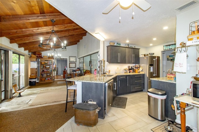 kitchen with vaulted ceiling, a sink, a peninsula, stainless steel appliances, and visible vents