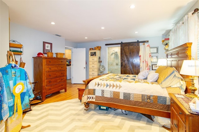 bedroom featuring a barn door, visible vents, wood finished floors, and recessed lighting