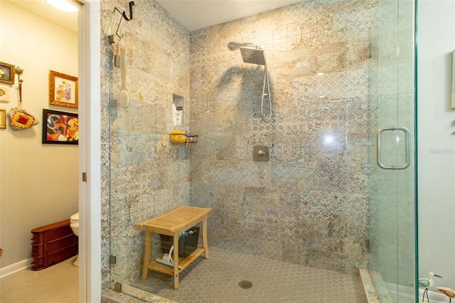 bathroom with toilet, a stall shower, tile patterned flooring, and baseboards
