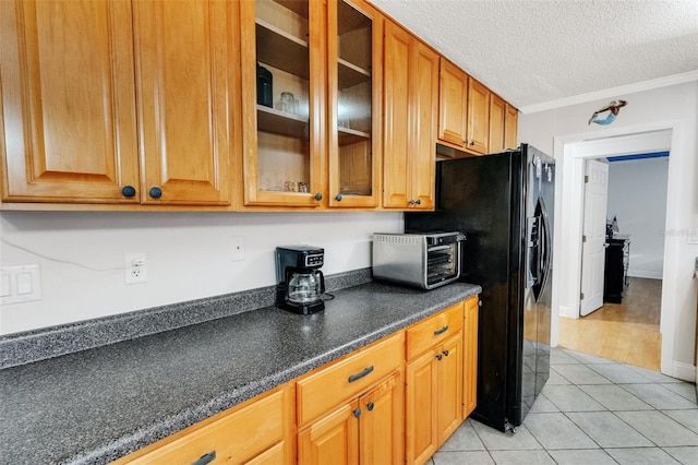 202 Saint Lucie Rd, Winter Haven, FL 33884 - kitchen with black fridge with ice dispenser, glass insert cabinets, light tile patterned floors, crown molding, and a textured ceiling
