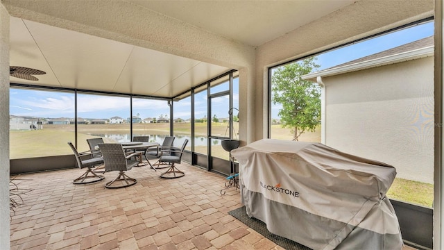 sunroom / solarium with a water view and outdoor dining area