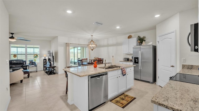 kitchen featuring white cabinets, decorative light fixtures, stainless steel appliances, and plenty of natural light