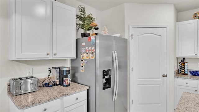 kitchen with white cabinetry, stainless steel fridge with ice dispenser, light stone counters, and a toaster