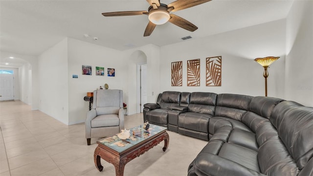 living room with arched walkways, a ceiling fan, visible vents, and light tile patterned floors