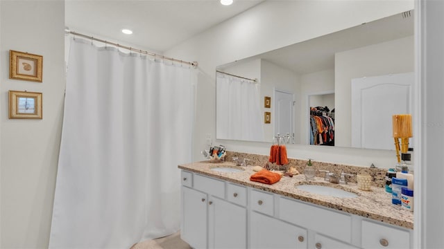 full bathroom featuring double vanity, a sink, a walk in closet, and recessed lighting