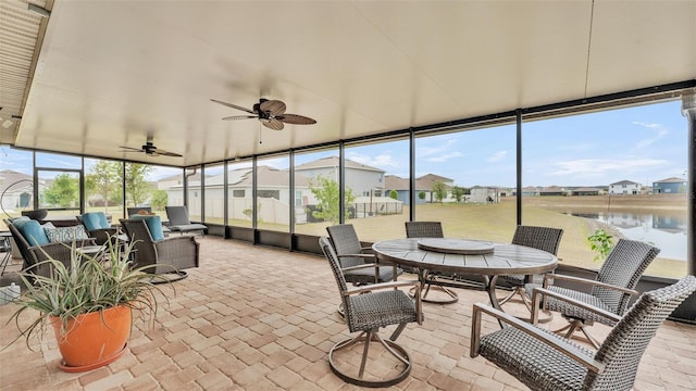 sunroom / solarium with outdoor dining area, a water view, and a ceiling fan