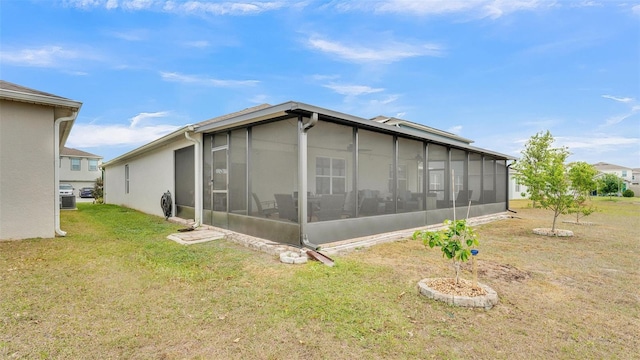 view of property exterior featuring a lawn, a sunroom, and stucco siding
