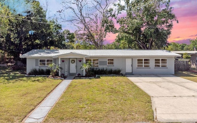 2410 NW Ave B, Winter Haven, FL 33880 - ranch-style house with a front lawn, concrete driveway, and a metal roof