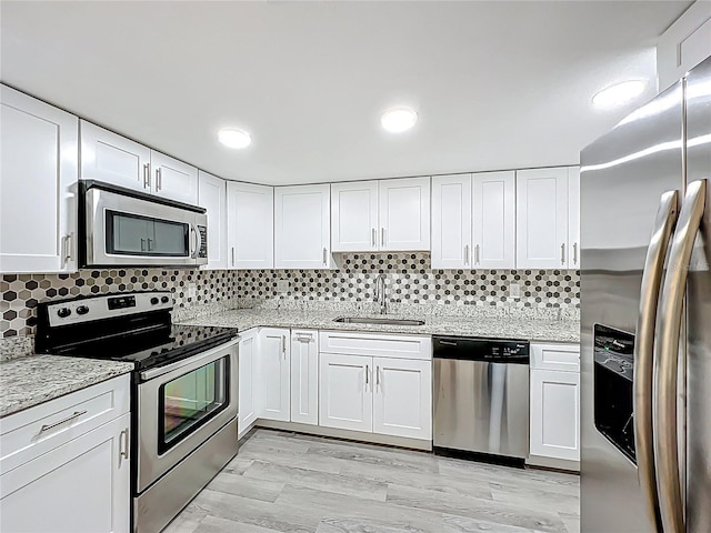 2042 Windward Pass, Lakeland, FL 33813 - kitchen with white cabinetry, light stone counters, a sink, and stainless steel appliances