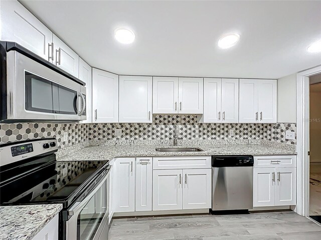 2042 Windward Pass, Lakeland, FL 33813 - kitchen with a sink, backsplash, white cabinetry, light stone countertops, and appliances with stainless steel finishes