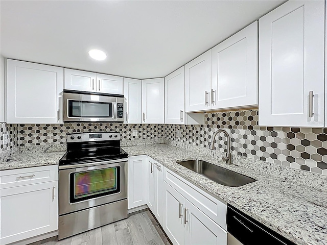 2042 Windward Pass, Lakeland, FL 33813 - kitchen with decorative backsplash, white cabinets, light stone countertops, stainless steel appliances, and a sink