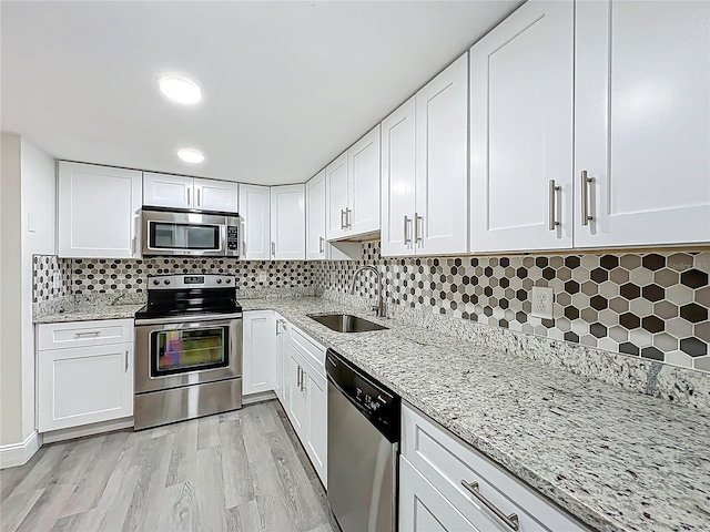2042 Windward Pass, Lakeland, FL 33813 - kitchen featuring white cabinetry, tasteful backsplash, stainless steel appliances, a sink, and light stone counters