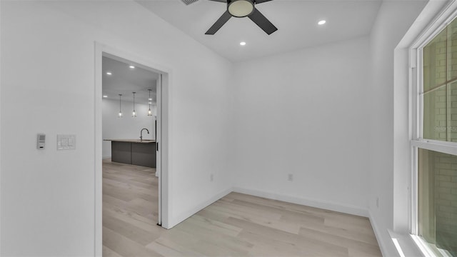 empty room with a sink, light wood-type flooring, recessed lighting, ceiling fan, and baseboards