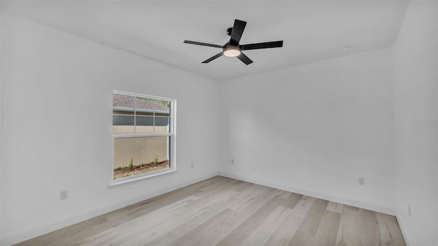 spare room with ceiling fan, light wood-style flooring, and baseboards