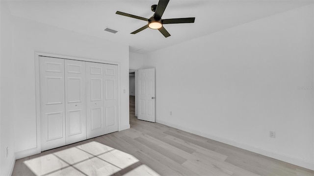 unfurnished bedroom featuring light wood-type flooring, baseboards, a closet, and visible vents