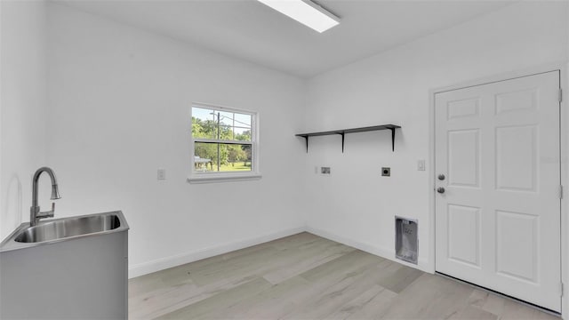 washroom featuring a sink, laundry area, light wood-style flooring, electric dryer hookup, and baseboards