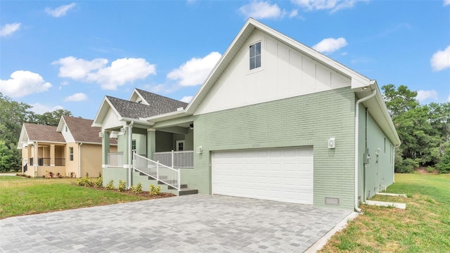 exterior space featuring brick siding, a yard, a garage, decorative driveway, and board and batten siding