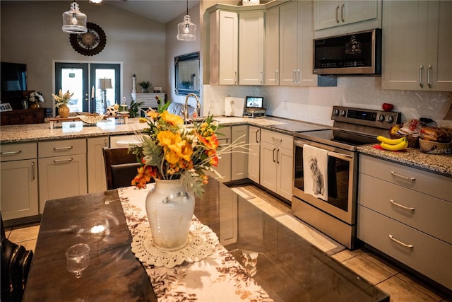 811 W Heron Pl, Winter Haven, FL 33884 - kitchen with stainless steel appliances, light tile patterned floors, vaulted ceiling, light stone countertops, and a peninsula