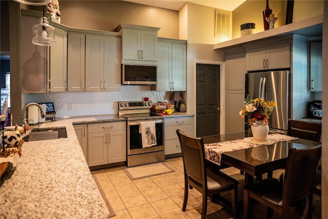 811 W Heron Pl, Winter Haven, FL 33884 - kitchen with appliances with stainless steel finishes, tasteful backsplash, light tile patterned floors, hanging light fixtures, and light stone counters