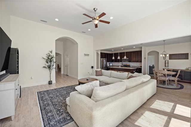 living room with arched walkways, visible vents, recessed lighting, and ceiling fan with notable chandelier