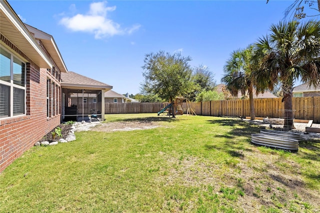 view of yard with a fenced backyard, a sunroom, and a playground