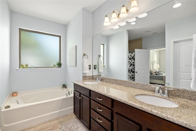 bathroom with double vanity, a bath, wood finished floors, and a sink
