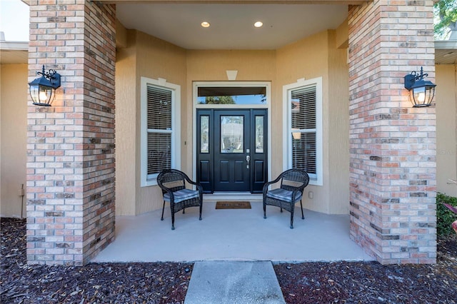property entrance with brick siding and stucco siding