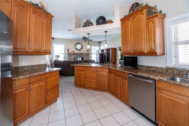 kitchen featuring brown cabinets, a stone fireplace, appliances with stainless steel finishes, and open floor plan