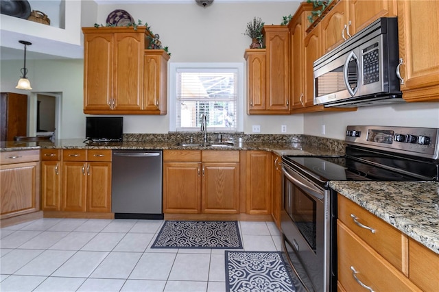 kitchen with dark stone counters, brown cabinetry, stainless steel appliances, and a sink