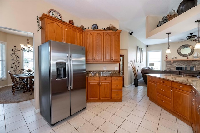 kitchen with a glass covered fireplace, brown cabinetry, open floor plan, and stainless steel fridge with ice dispenser