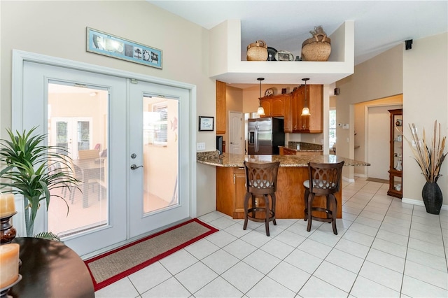 kitchen with a wealth of natural light, french doors, stainless steel fridge, and brown cabinets