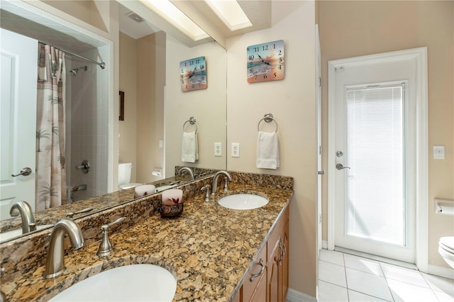 full bathroom with toilet, tile patterned floors, a sink, and a skylight