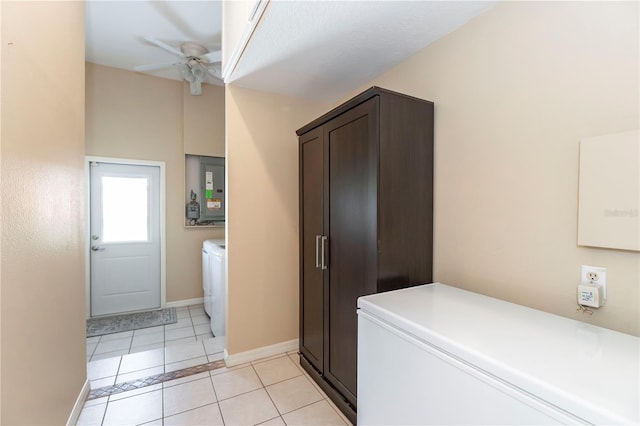 washroom with a ceiling fan, light tile patterned floors, washing machine and dryer, baseboards, and laundry area