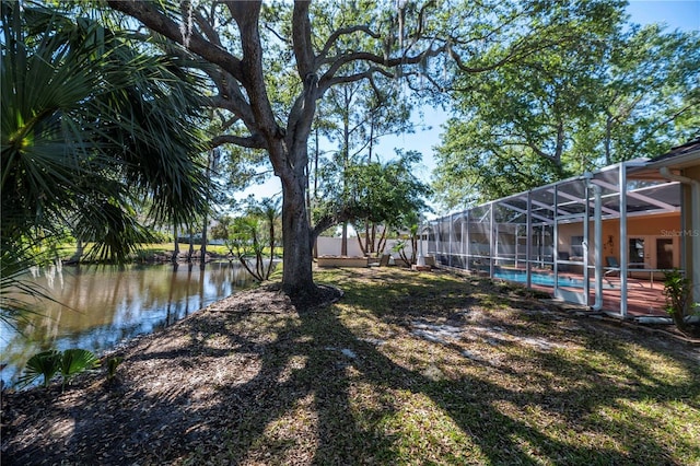 view of yard featuring a lanai, a fenced in pool, and a water view