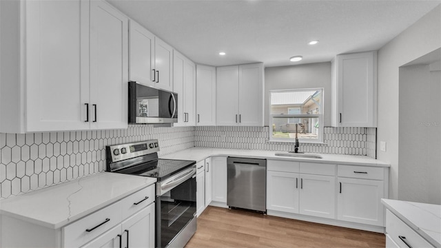 1650 W Mcleod St, Bartow, FL 33830 - kitchen featuring stainless steel appliances, a sink, light stone counters, tasteful backsplash, and white cabinetry