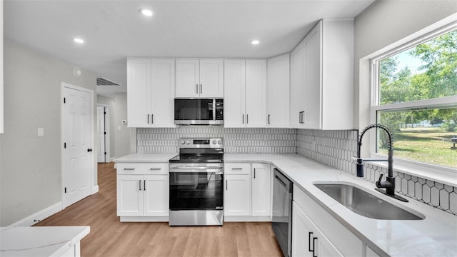 1650 W Mcleod St, Bartow, FL 33830 - kitchen featuring appliances with stainless steel finishes, a sink, tasteful backsplash, light wood-style flooring, and light stone counters